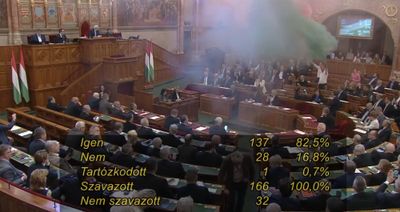 Coloured smoke drifts across Hungary's parliament chamber as the screen shows the vote passing 137 to 28.