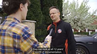 A reporter holds a microphone to Péter Szijjártó outside a house, with subtitles from the interview.